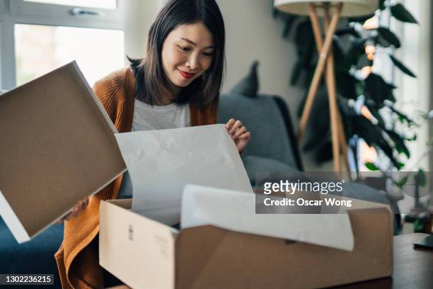 beautiful young woman receiving parcel purchased online - debit cards credit cards accepted stock pictures, royalty-free photos & images