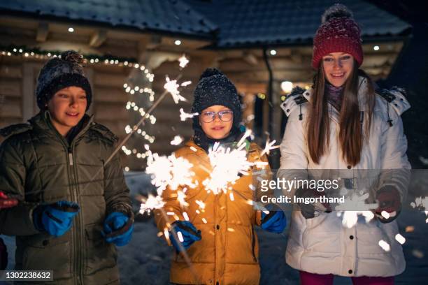 children enjoying sparklers at winter night - friends with sparkler fireworks stock pictures, royalty-free photos & images