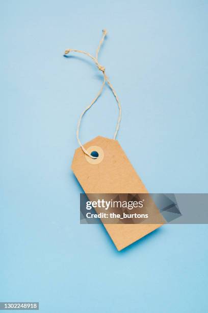 still life of a blank brown paper price tag on blue colored background - gift tag imagens e fotografias de stock