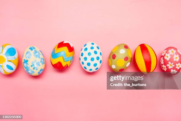 directly above shot of colourful painted easter eggs on pink background - easter egg stockfoto's en -beelden