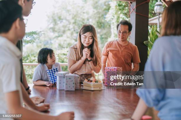 donna cinese che festeggia il suo compleanno facendo desideri e soffiando candela con amici e familiari nel cortile di casa durante il fine settimana - parents children blow candles asians foto e immagini stock