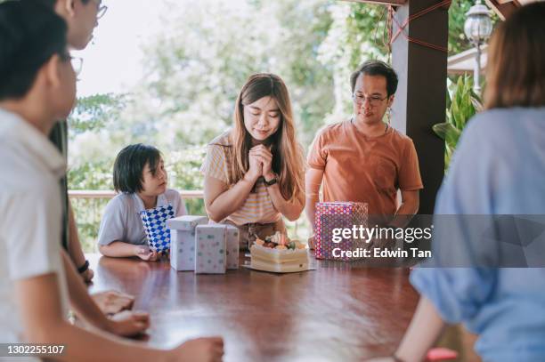 chinese vrouw die haar verjaardag viert die wensen maakt en kaars met vrienden en familie bij binnenplaats van huis tijdens weekend blaast - chinese birthday stockfoto's en -beelden