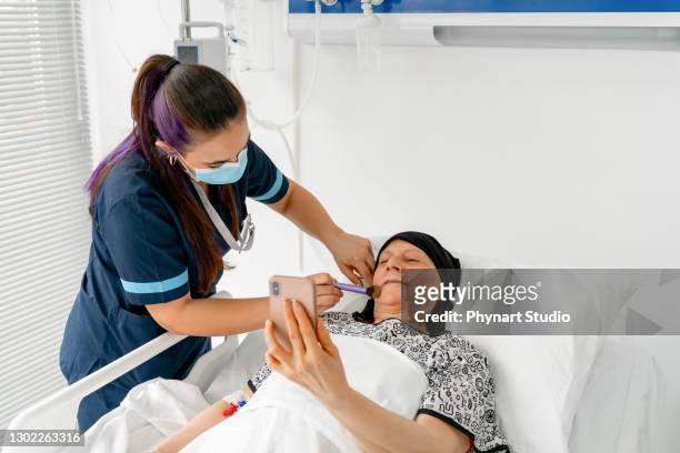 verpleegster die make-up op een patiënt zet wiens kankerbehandeling aan de gang is - hospitium stockfoto's en -beelden