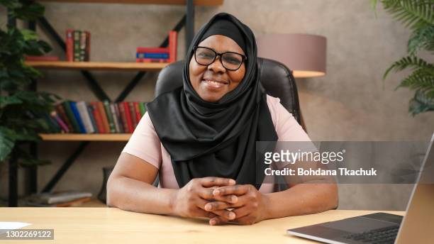 african-american old lady in glasses and black hijab looking at camera - woman look straight black shirt stock pictures, royalty-free photos & images