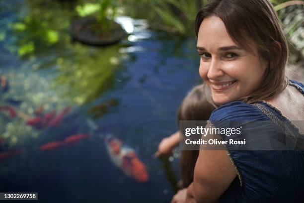 smiling woman at garden pond with daughter - water garden stock pictures, royalty-free photos & images