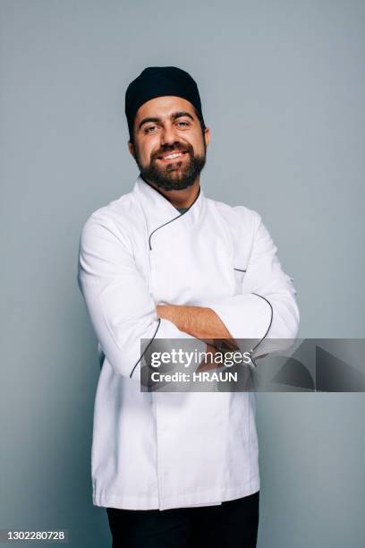 chef adulto medio in uniforme su sfondo grigiastro - chef foto e immagini stock