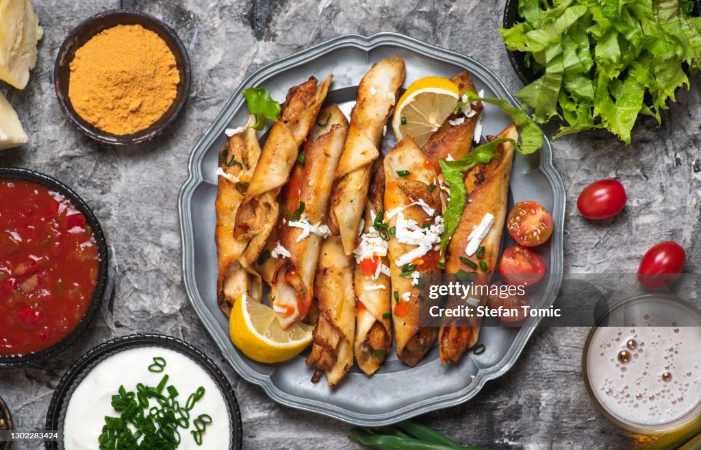 Homemade chicken taquitos dorados with dipping sauces and food ingredients