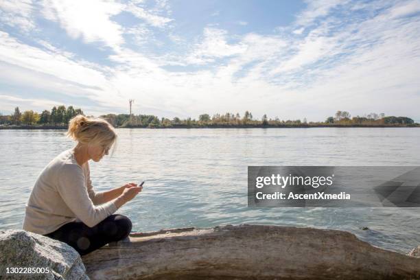 donna usa smartphone sulla riva del fiume - fraser foto e immagini stock