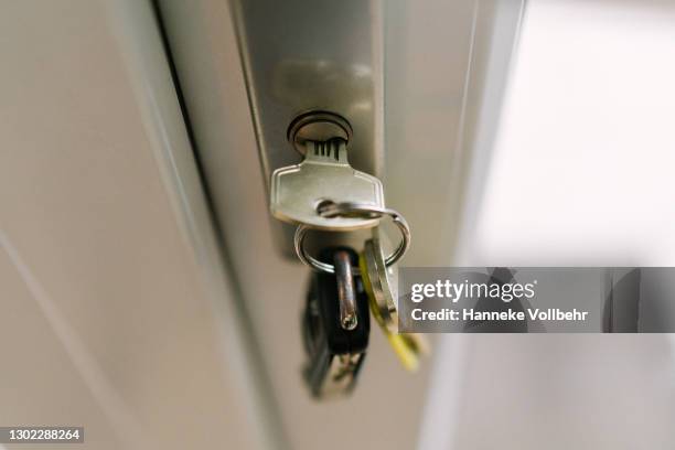 bunch of keys hanging in a door lock. - key in door stock-fotos und bilder