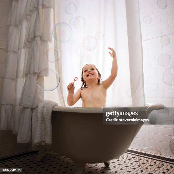 little girl in bathtub blowing bubbles. - baby bath toys stock pictures, royalty-free photos & images