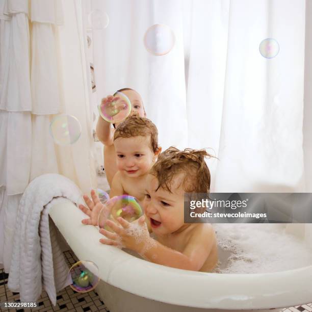 baby's in badkuip die in een bubbelbad spelen. - bubbelbad stockfoto's en -beelden