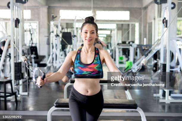 young fitness woman execute exercise with exercise-machine cable crossover in gym. - capital punishment stock pictures, royalty-free photos & images
