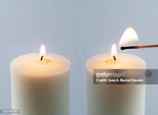 close-up of match lighting a candle against white background. - candle white background stock-fotos und bilder