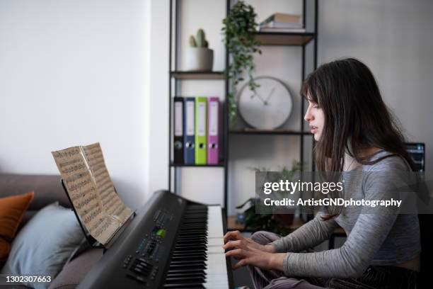 female musician playing piano at home during quarantine. - electric piano stock pictures, royalty-free photos & images