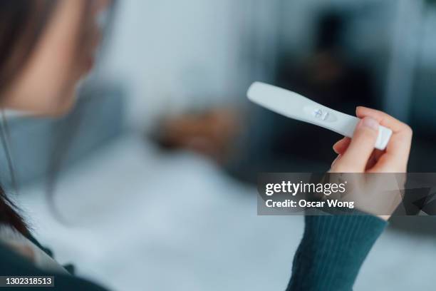 senior woman holding home pregnancy test and looking surprised - film festival screening of behind the curve stockfoto's en -beelden