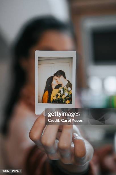 young female showing instant instant photo image of a young couple kising - cute girlfriends stockfoto's en -beelden