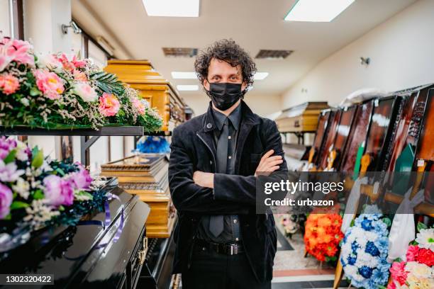 undertaker in funeral parlor with face mask - funeral merchandise stock pictures, royalty-free photos & images