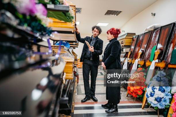 begrafenisondernemer die doodskisten aan een weduwe toont - coffin stockfoto's en -beelden