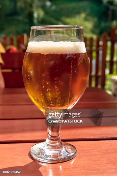 glass of cold craft beer standing on a table outdoors. - ale stock pictures, royalty-free photos & images