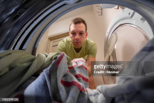 handsome man taking out clean washed clothes from drying after washing - sheet bedding stock-fotos und bilder