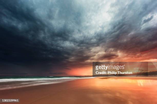 ritiro di marea che riflette una tempesta drammatica sulla spiaggia al tramonto - cielo variabile foto e immagini stock