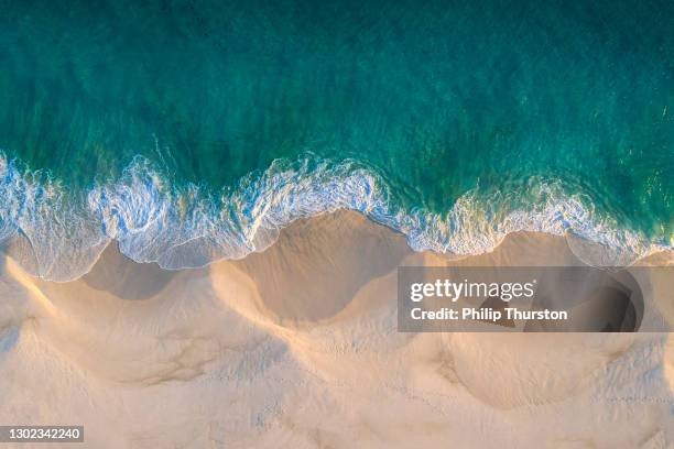 aerial view of white sand beach coastline and swirling waves with teal blue ocean - sand stock pictures, royalty-free photos & images