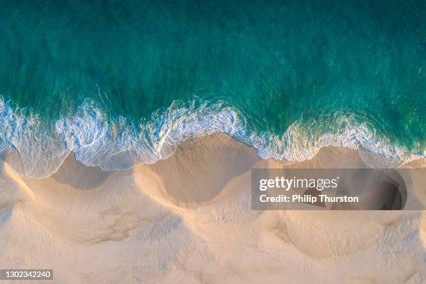 vista aérea do litoral da praia de areia branca e ondas giratórias com oceano azul de teal - maré - fotografias e filmes do acervo