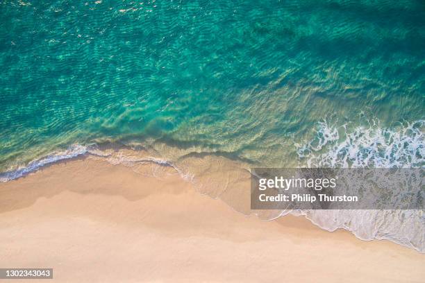 saubere meereswellen brechen auf weißem sandstrand mit türkis smaragdfarbenem wasser - wasserrand stock-fotos und bilder