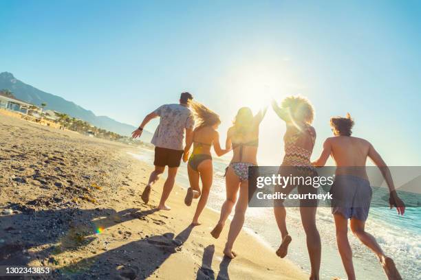 一群朋友在日落時分奔跑和跳入大海。 - marbella 個照片及圖片檔