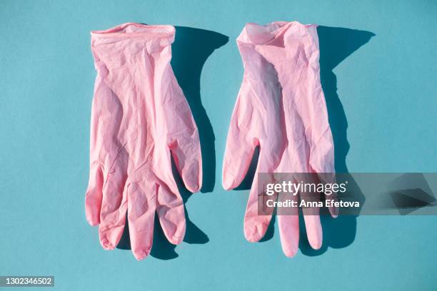 pink protective gloves for doctor on blue background - roze handschoen stockfoto's en -beelden