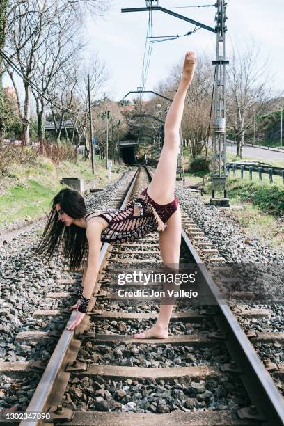 a young female gymnast is performing artistic movements on the train tracks in her typical competition costume. - adult gymnast feet stock-fotos und bilder