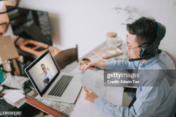 high angle side view asian chinese mid adult man having discussion with his lecturer online with laptop and headset at home - working on laptop in train top view stock pictures, royalty-free photos & images