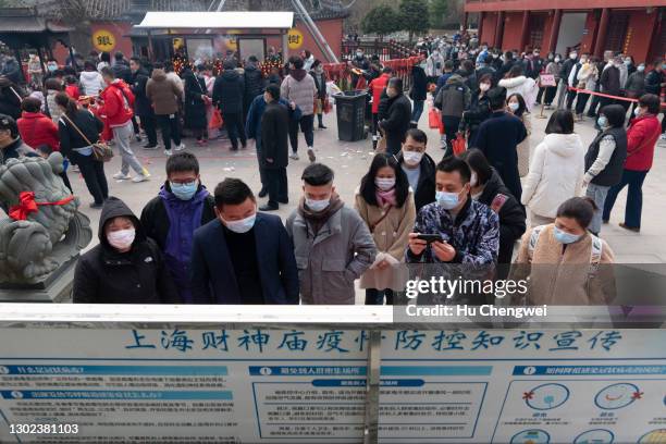 People read a notice on COVID-19 regulations as they gather to pray at a temple on February 16, 2021 in Shanghai, China. Today marks the fifth day of...