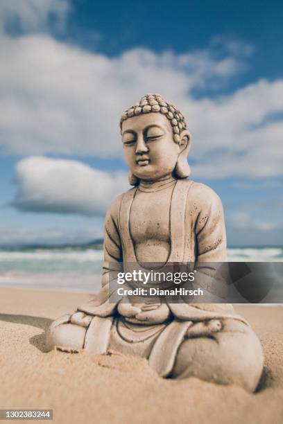 hermosa figura de piedra de buda sentada a orillas del mar frente al mar - buddah fotografías e imágenes de stock