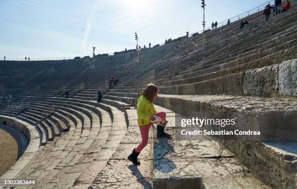 the little girl climbs the steps with difficulty, arena di verona amphitheatre, italy. - verona italy stock pictures, royalty-free photos & images