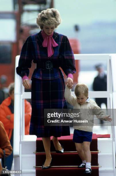 Diana, Princess of Wales, wearing a pink and purple tartan suit, and Prince William, wearing a cable knit cardigan and blue shorts, leave the Royal...