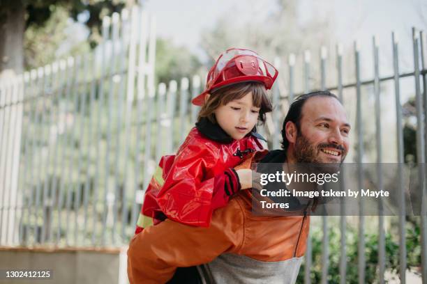 father carrying in the back his son in a fireman costume - autism awareness stock pictures, royalty-free photos & images
