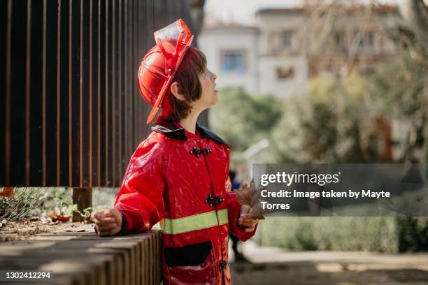 boy in the park holding a leave and wearing a fireman costume - boy fireman costume stock pictures, royalty-free photos & images