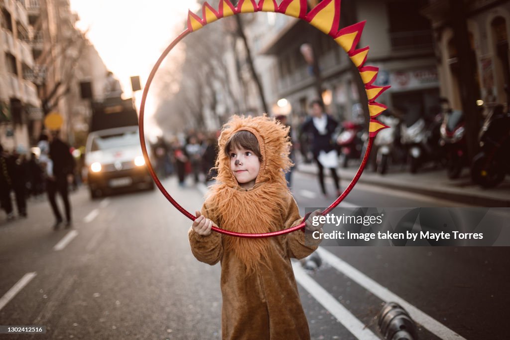 Boy dressed as a lion in the street with ring of fire