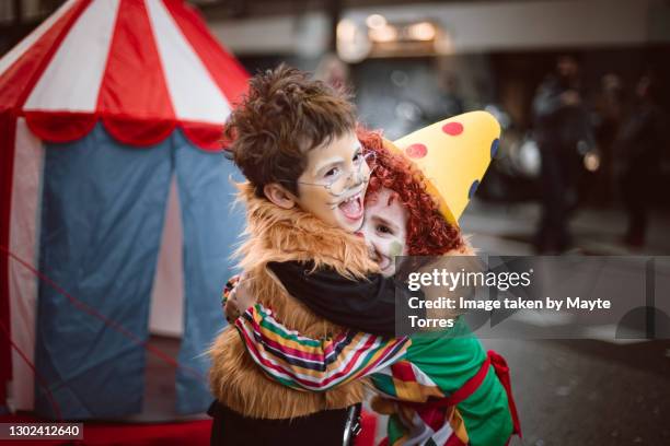 boy dressed as a lion embracing boy dressed as a clown looking excited - zirkus stock-fotos und bilder