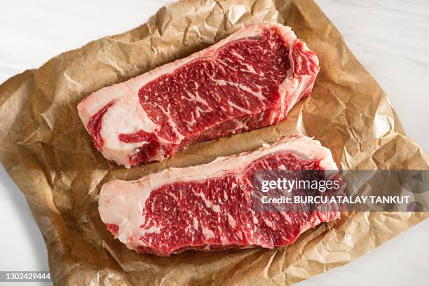 two slices of sirloin steak on butcher paper - butcher paper foto e immagini stock