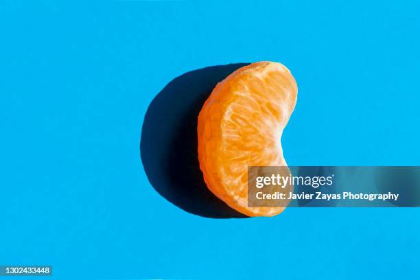 fresh tangerine segment on blue background - segments fotografías e imágenes de stock