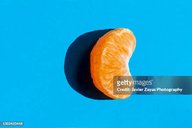 fresh tangerine segment on blue background - tangerine stock pictures, royalty-free photos & images
