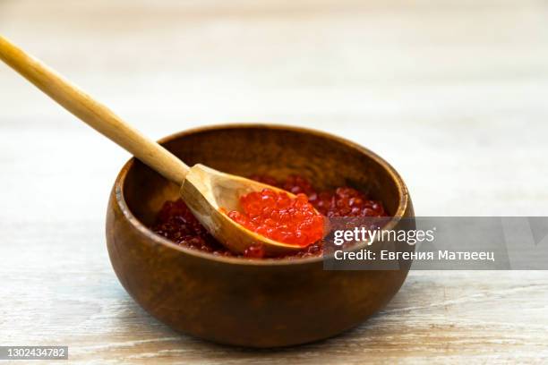 fresh red caviar in bamboo bowl with wooden spoon on rustic bleached white wood table background - kaviar stock-fotos und bilder