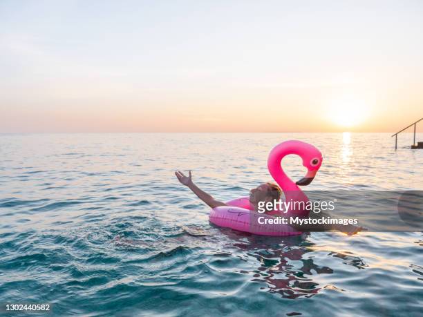 frau schwimmt mit aufblasbarem flamingo im meer - flamingos stock-fotos und bilder