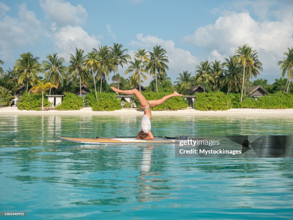 Mujer hace ejercicio postura de yoga en stand up paddle