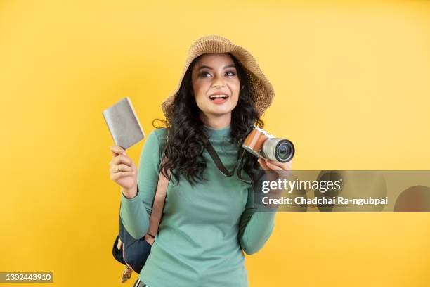 portrait photo of young beautiful asian woman feeling happy and holding camera and passport with black empty screen on yellow background can use for advertising or product presenting concept. - portraits of people passport fotografías e imágenes de stock