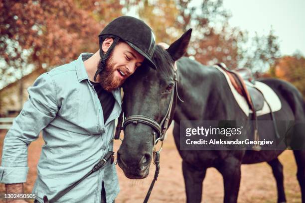 modern male jockey embracing horse after fun day riding on ranch - macedonia country stock pictures, royalty-free photos & images