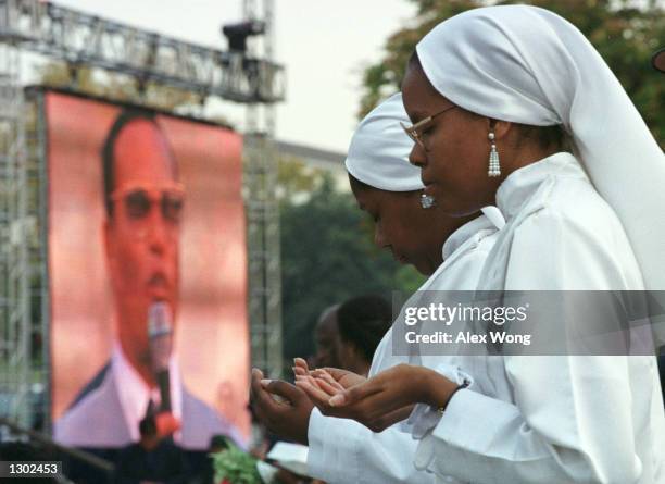 Two members of Fruit of Islam pray as the Nation of Islam leader Louis Farrakhan is seen on a jumboton screen during the Million Family March October...