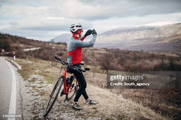 professional cyclist taking pictures with phone by the road - white glove phone stock pictures, royalty-free photos & images